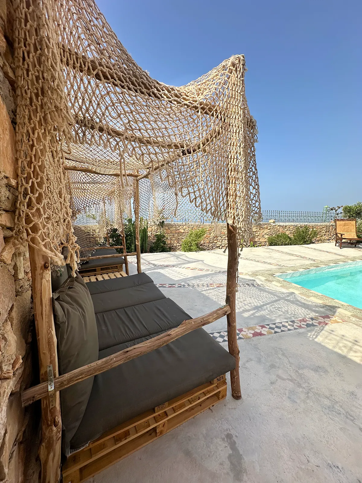 Guests enjoying Taghazout Accommodation relaxing by the ocean-view pool at Taghazout Surf Villa
