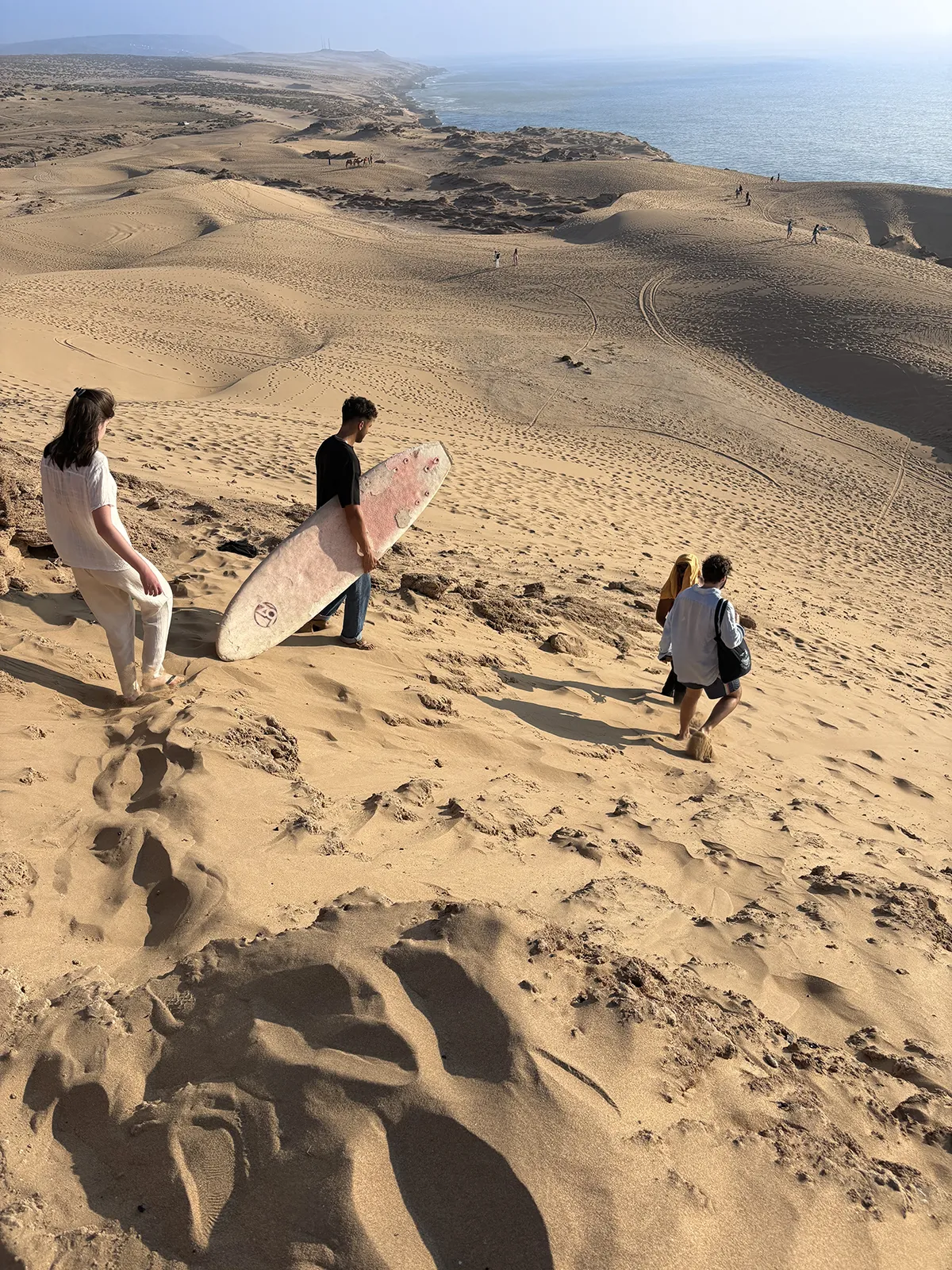 Guests sandboarding on desert dunes near Taghazout during an off-day excursion with Taghazout Surf Villa