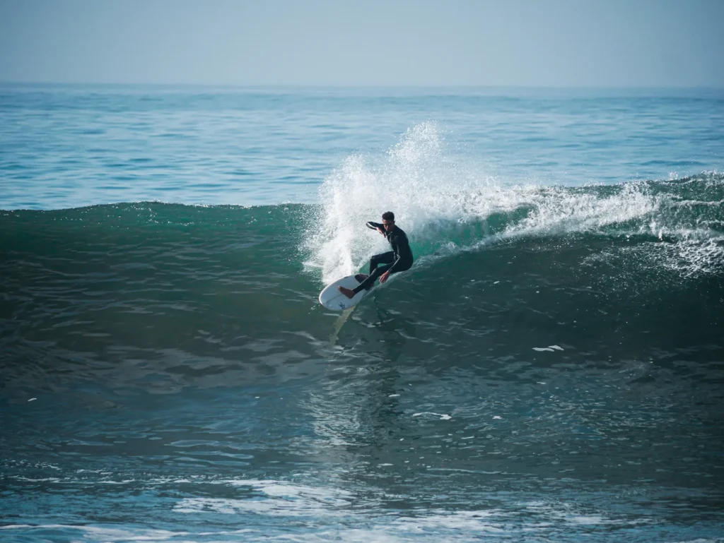 Surfer riding a wave at Anchor Point during a surf camp in Morocco hosted by Taghazout Surf Villa, enjoying professional surf lessons and Taghazout surfing adventure.
